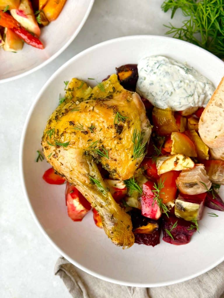 Oven roasted spatchcock chicken leg served over roasted root vegetables with herby yogurt sauce and fresh dill.