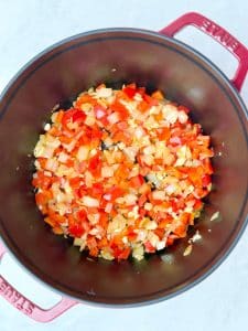 Diced onion, red bell pepper, and garlic sautéing in olive oil in a red Dutch oven for high-protein taco soup.