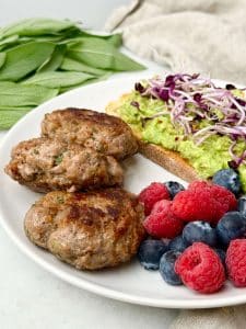 Turkey breakfast sausage patties served with avocado toast, blueberries, and raspberries for a healthy high-protein breakfast.