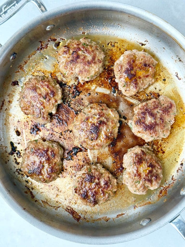 Turkey breakfast sausage patties sizzling in a stainless steel skillet for a healthy meal prep breakfast.