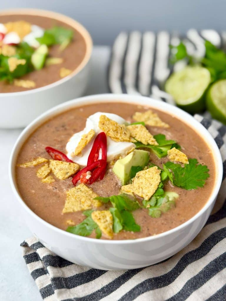 Creamy high-protein black bean soup topped with Greek yogurt, avocado, cilantro, red chili, and tortilla chips.