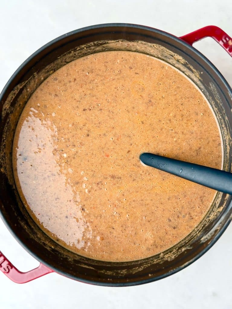 Smooth blended black bean soup simmering in a Dutch oven.