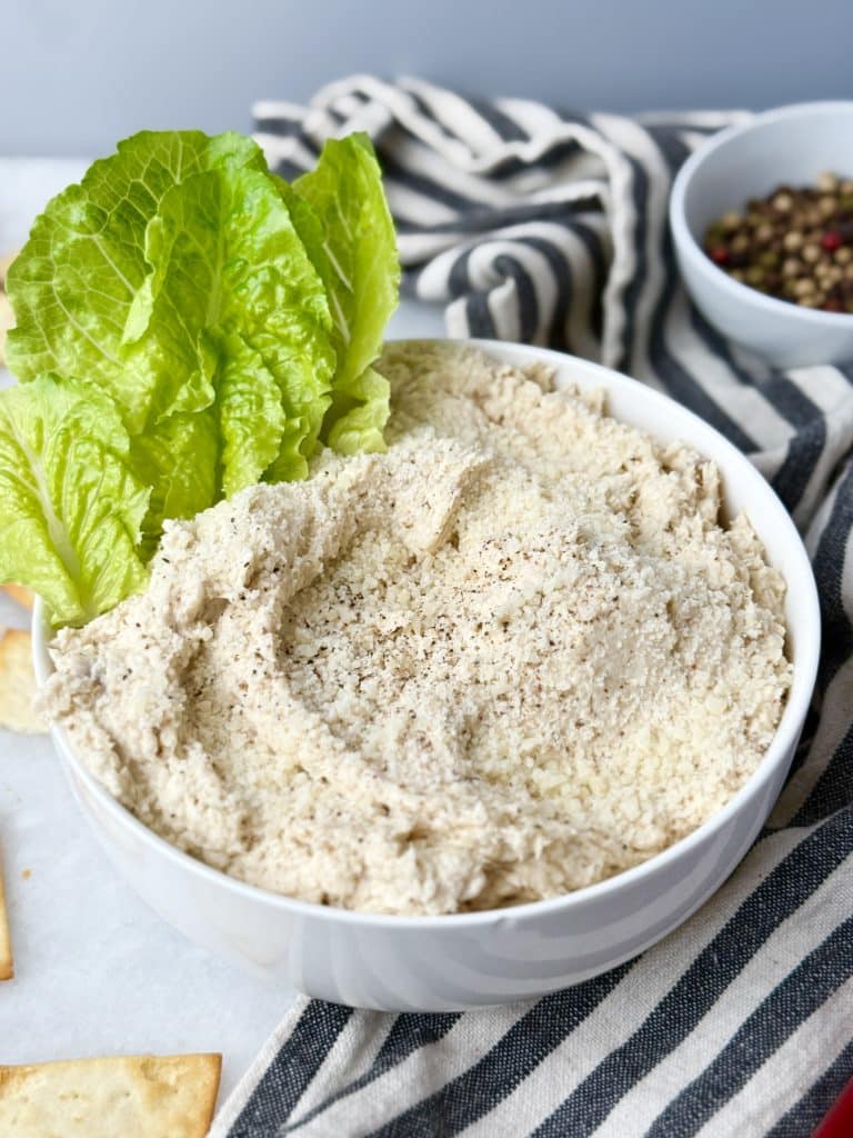 Close-up of creamy chicken salad with romaine leaves and Parmesan on top, served in a white bowl for a high-protein lunch.