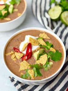 Side view of a bowl of creamy high-protein black bean soup with bold Mexican toppings.