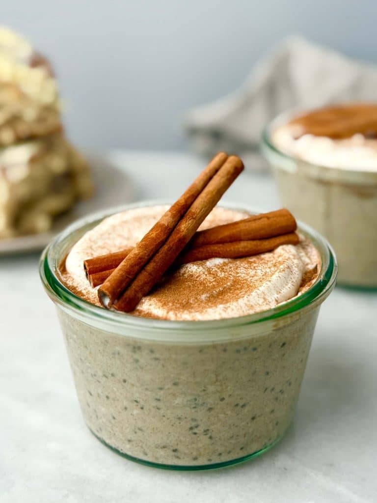 Creamy high-protein cinnamon roll overnight oats topped with cinnamon sticks.
