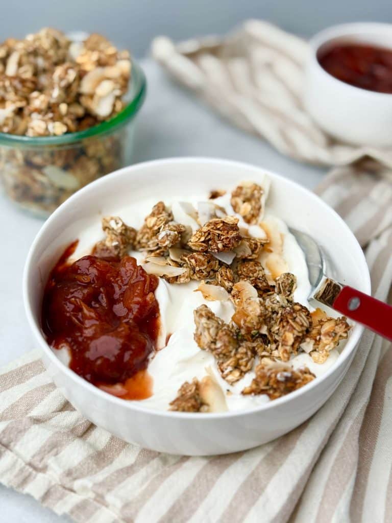 Protein granola served over a bowl of Greek yogurt with fruit preserves.