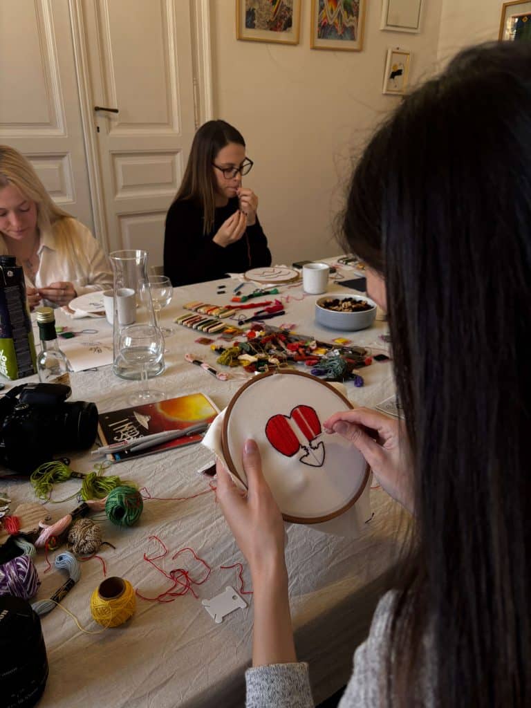 Group of women hand embroidering colorful designs during a nostalgic old-school craft hobby.