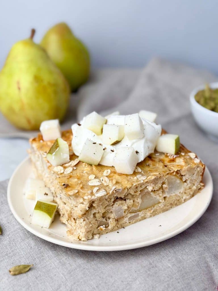 Thick slice of pear cardamom baked oat bars topped with diced pear and yogurt.