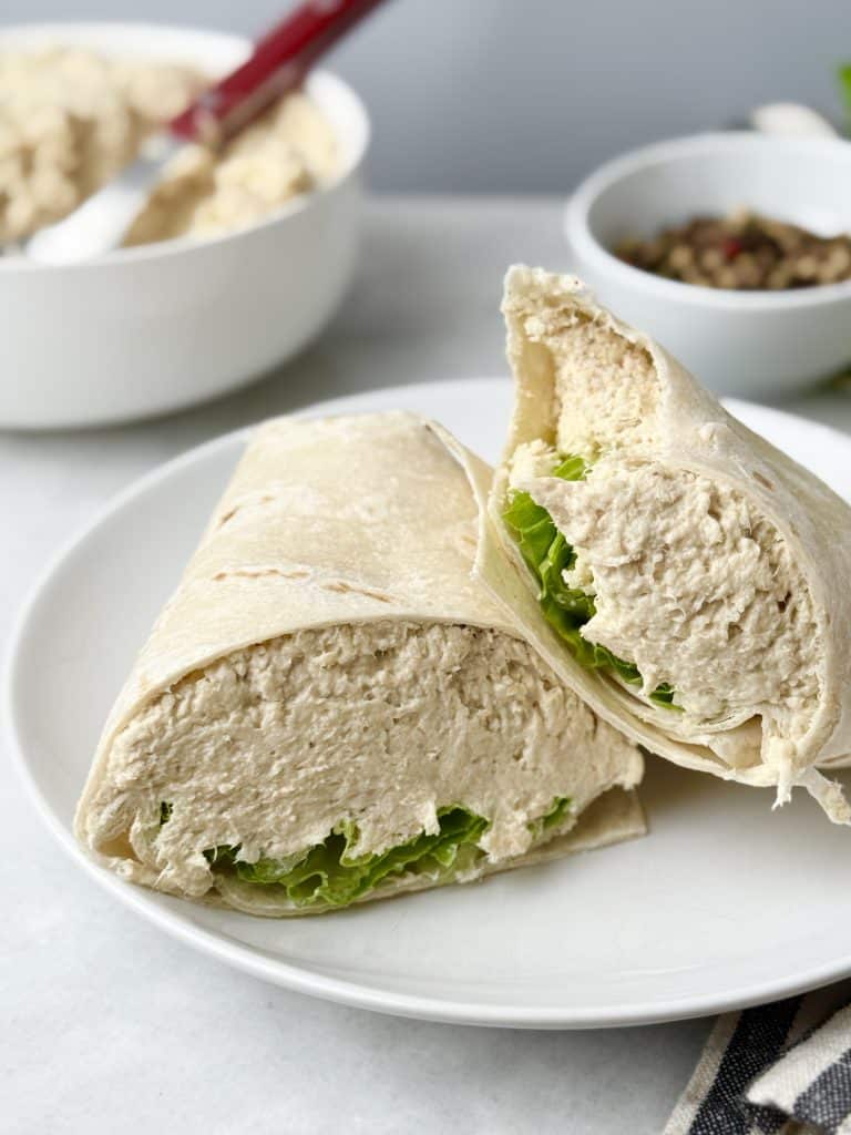 Creamy Caesar rotisserie chicken salad wrap cut in half on a white plate, filled with shredded chicken and crisp romaine lettuce for an easy high-protein lunch.