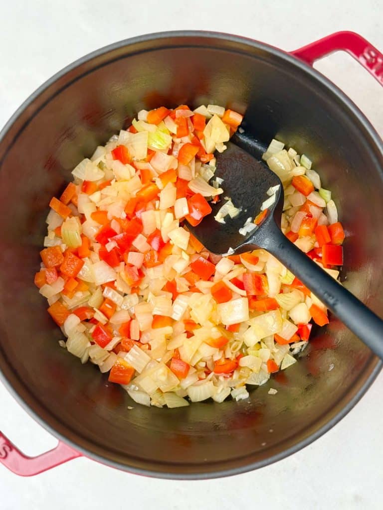 Sautéed onions and red bell peppers forming the flavor base for black bean soup.