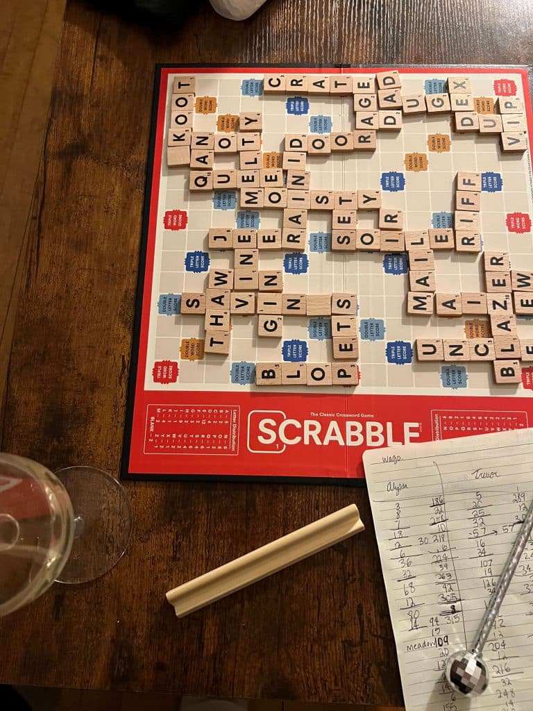 Cozy game night with a Scrabble board and handwritten score sheet, a nostalgic old-school hobby that encourages slow living and connection.