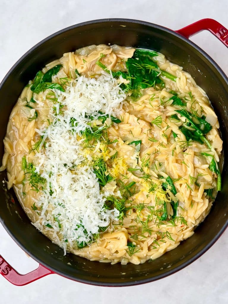 Stirring parmesan, fresh dill, lemon zest, and spinach into creamy lemon chicken orzo.