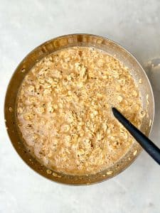 Almond croissant baked oatmeal mixture with rolled oats, almond butter, and almond extract mixed together in a large bowl.