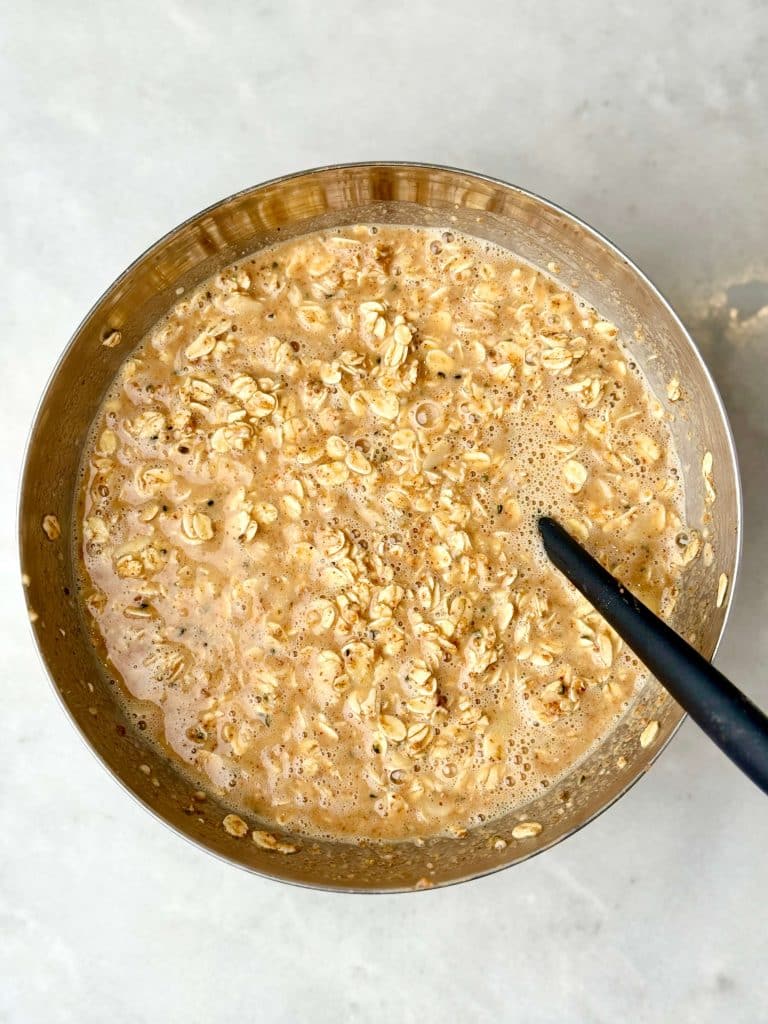 Almond croissant baked oatmeal mixture with rolled oats, almond butter, and almond extract mixed together in a large bowl.