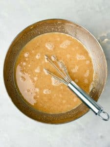 Wet ingredients for almond croissant baked oatmeal whisked together, including egg whites, almond butter, maple syrup, and almond extract.