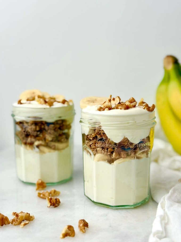 Banana bread–inspired yogurt parfaits made with Greek yogurt, banana slices, protein granola, and walnuts for a high-protein breakfast.