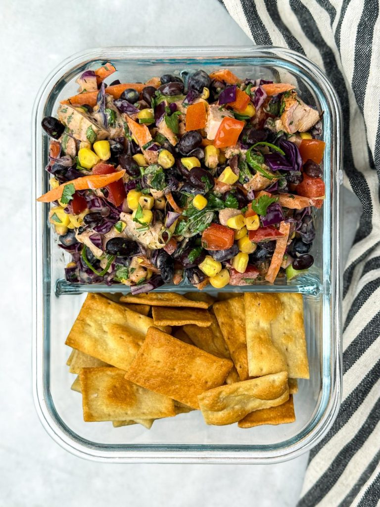BBQ chicken dense bean salad in a glass meal-prep container with pita chips