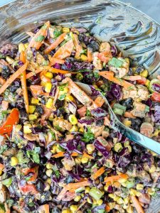 Close-up of BBQ chicken dense bean salad tossed in a glass mixing bowl