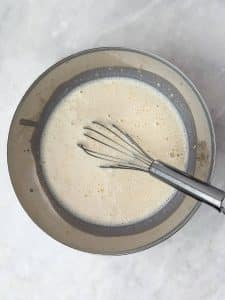 Whisking milk and protein powder together for creamy chai overnight oats before adding oats and spices.