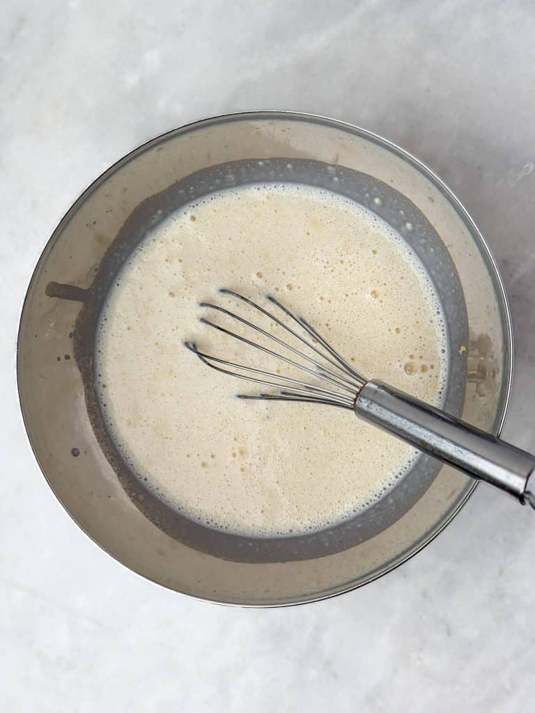 Whisking milk and protein powder together for creamy chai overnight oats before adding oats and spices.