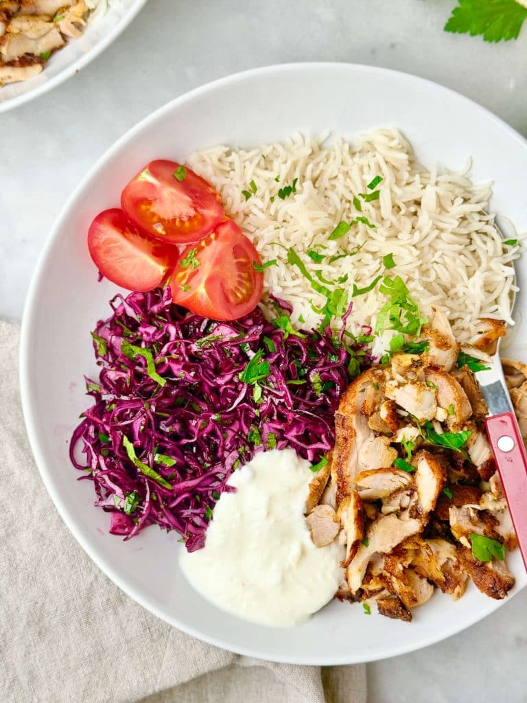 Chicken shawarma rice bowl made with air fryer chicken thighs, red cabbage salad, and garlic yogurt sauce.