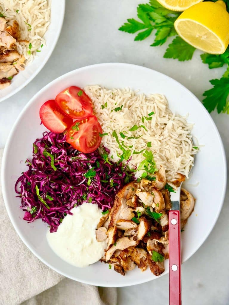 Air fryer chicken shawarma rice bowl served with yogurt sauce, fresh herbs, and lemon.