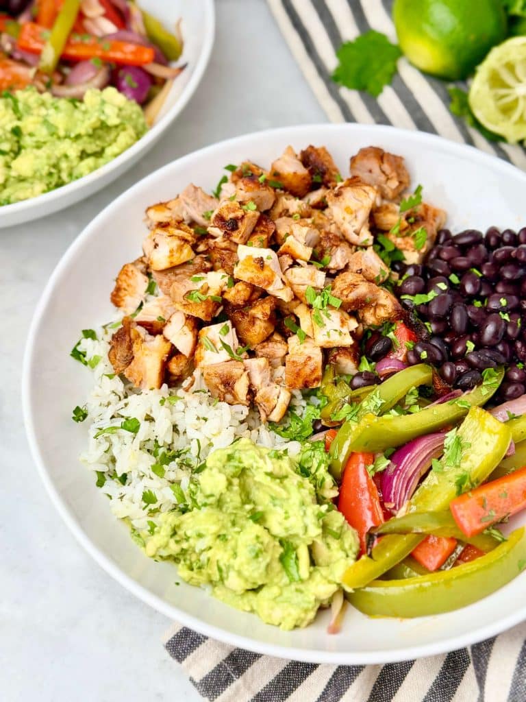Copycat Chipotle burrito bowl with air fryer chipotle chicken, cilantro lime rice, black beans, fajita vegetables, and fresh guacamole.