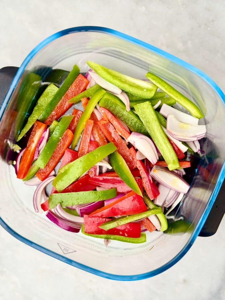 Sliced bell peppers and red onion prepared as Chipotle-style fajita vegetables for a homemade copycat Chipotle burrito bowl.
