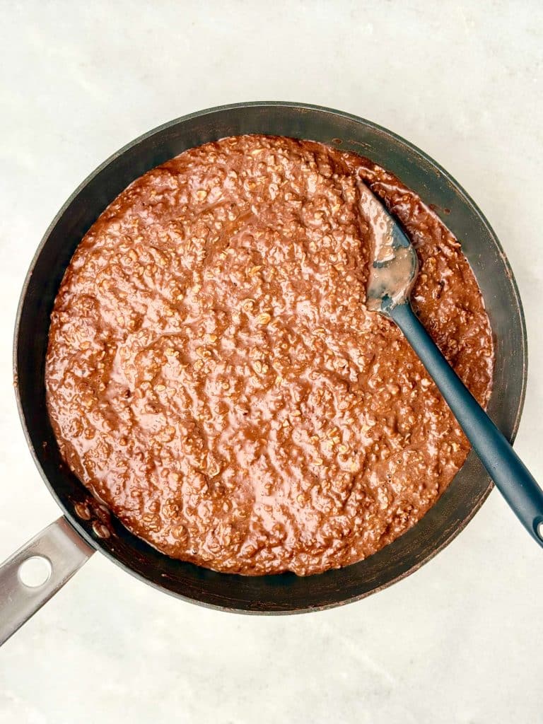Hot chocolate protein oats cooked on the stovetop, thick and creamy chocolate oatmeal in a saucepan