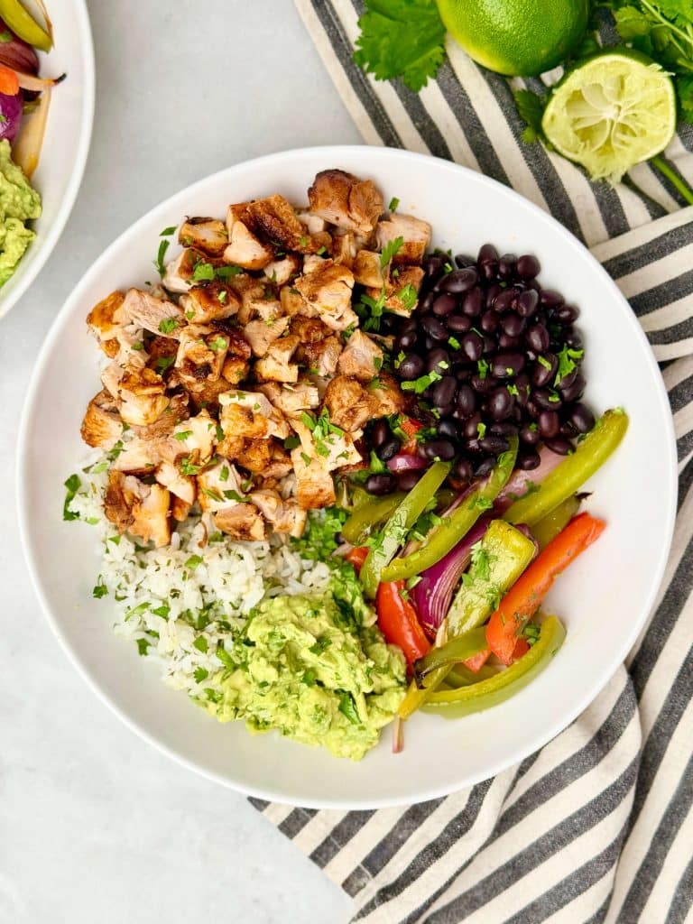 Copycat Chipotle burrito bowl with chipotle chicken, cilantro lime rice, black beans, fajita vegetables, and guacamole.