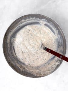 Creamy herb yogurt dressing in a metal bowl with a red spatula