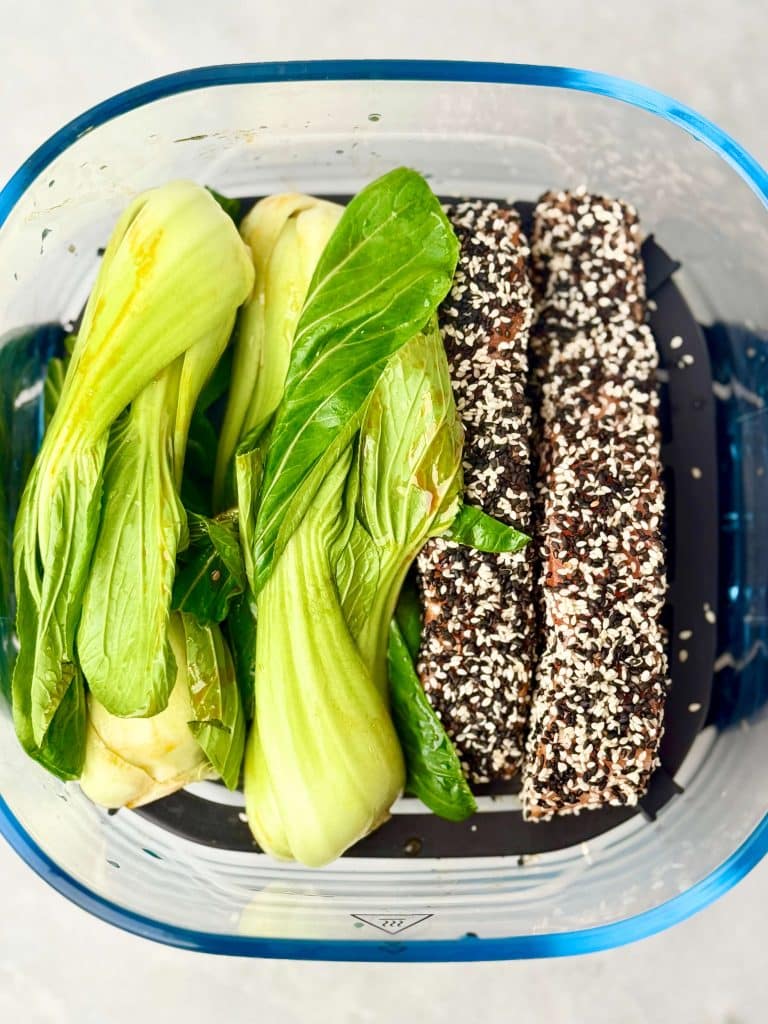 Raw sesame crusted salmon fillets and baby bok choy prepared for air frying