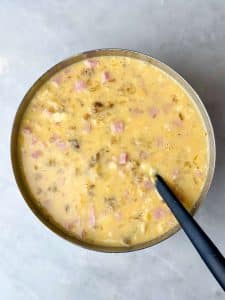 High protein breakfast casserole with ham, cheddar cheese, and grated potato mixture poured into a baking dish for an easy make-ahead breakfast.