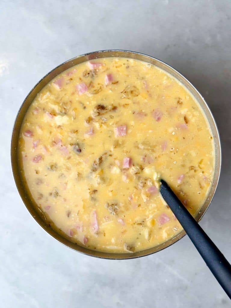 High protein breakfast casserole with ham, cheddar cheese, and grated potato mixture poured into a baking dish for an easy make-ahead breakfast.