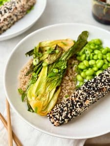 High protein salmon bowl with sesame crusted salmon, soy glazed bok choy, edamame, and rice topped with green onions