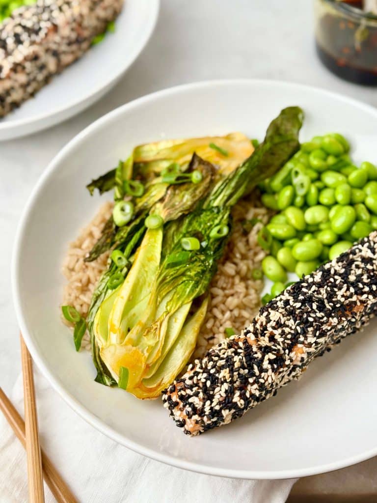 High protein salmon bowl with sesame crusted salmon, soy glazed bok choy, edamame, and rice topped with green onions