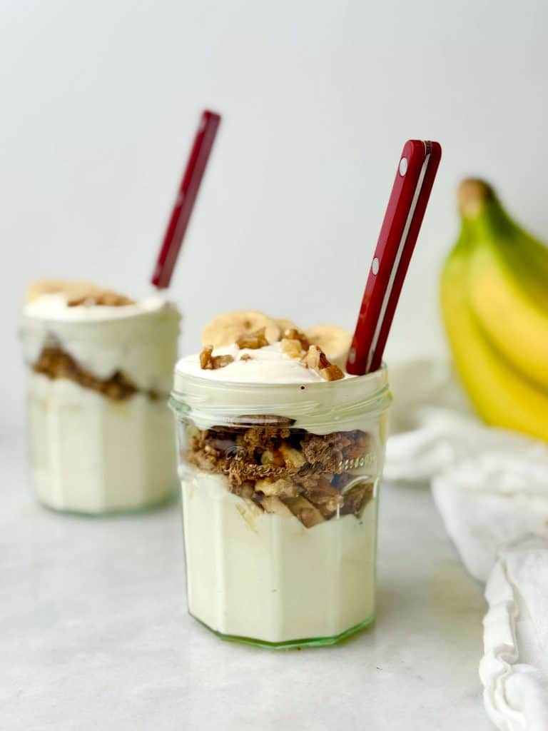 Banana yogurt parfait meal prep jar with Greek yogurt, sliced banana, protein granola, and walnuts, ready for an easy high-protein breakfast.