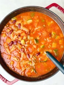 Homemade high protein minestrone soup cooking in a pot with tomato broth and vegetables