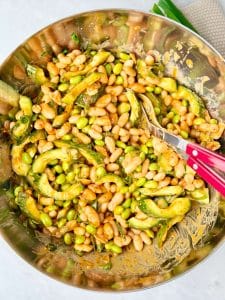 Miso edamame dense bean salad with white beans, sliced cucumber, green onions, and a spicy peanut miso dressing.