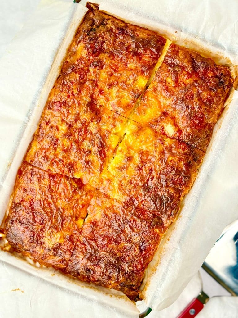 High protein egg casserole baked in a glass dish, cut into portions with a deeply golden, cheesy top.
