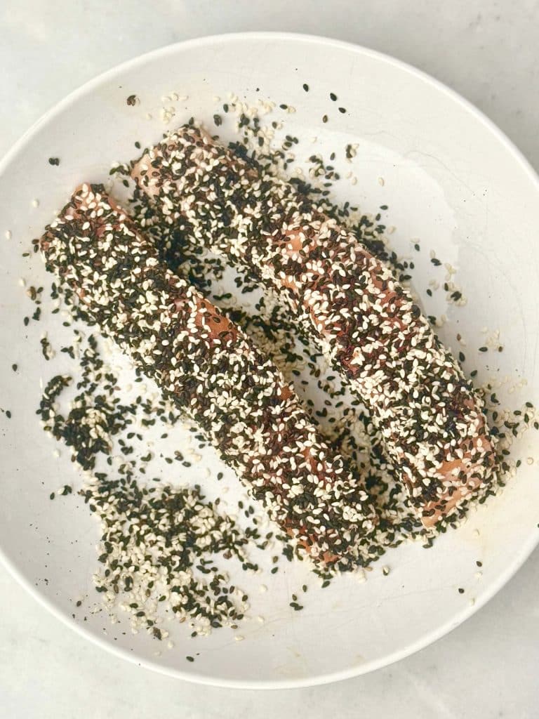 Salmon fillets coated in black and white sesame seeds before cooking