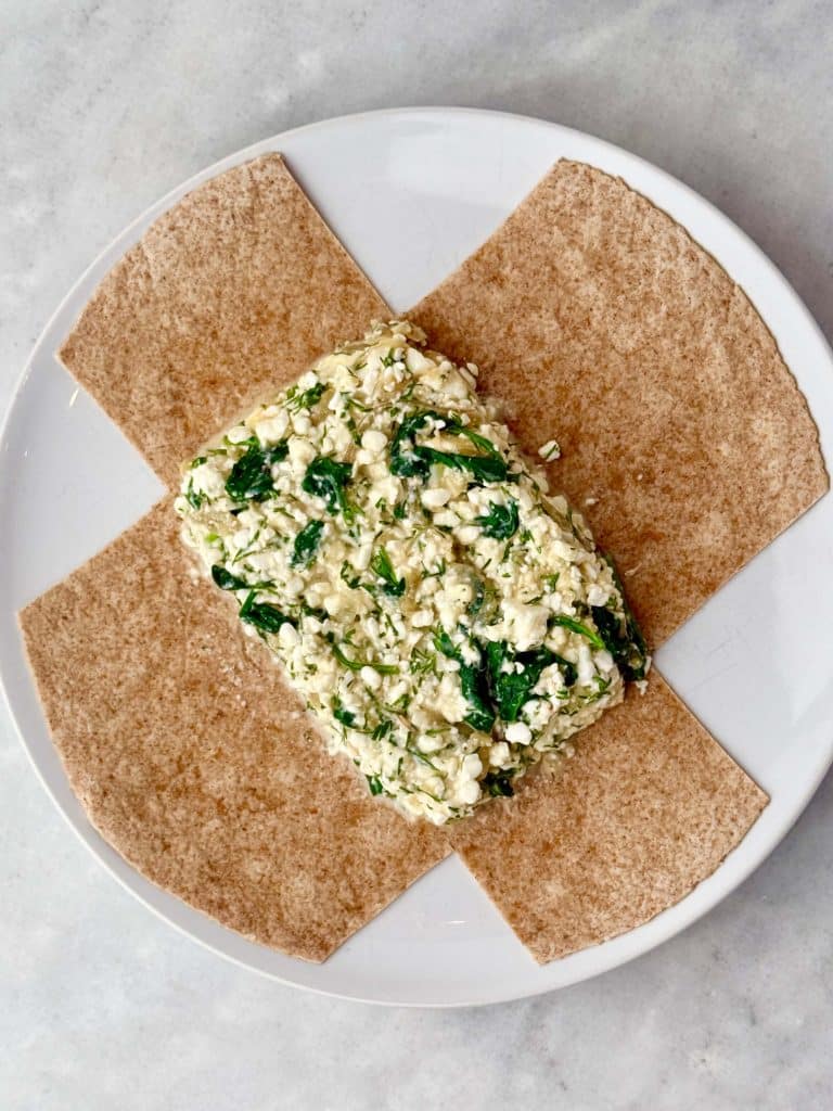 Spinach and feta filling layered onto a high-protein tortilla before wrapping