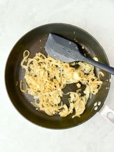 Sautéed onion and garlic cooking in a skillet for a spanakopita wrap