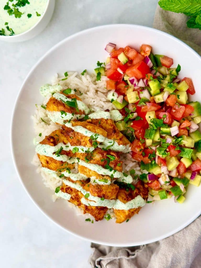 Healthy chicken tikka bowl with yogurt-marinated chicken, fluffy rice, and cucumber tomato salad