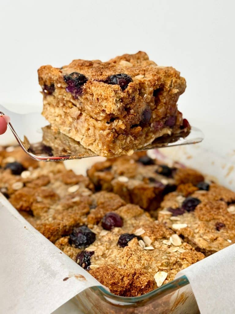 Side view of healthy blueberry muffin baked oats showing soft oat texture and bursts of baked blueberries.