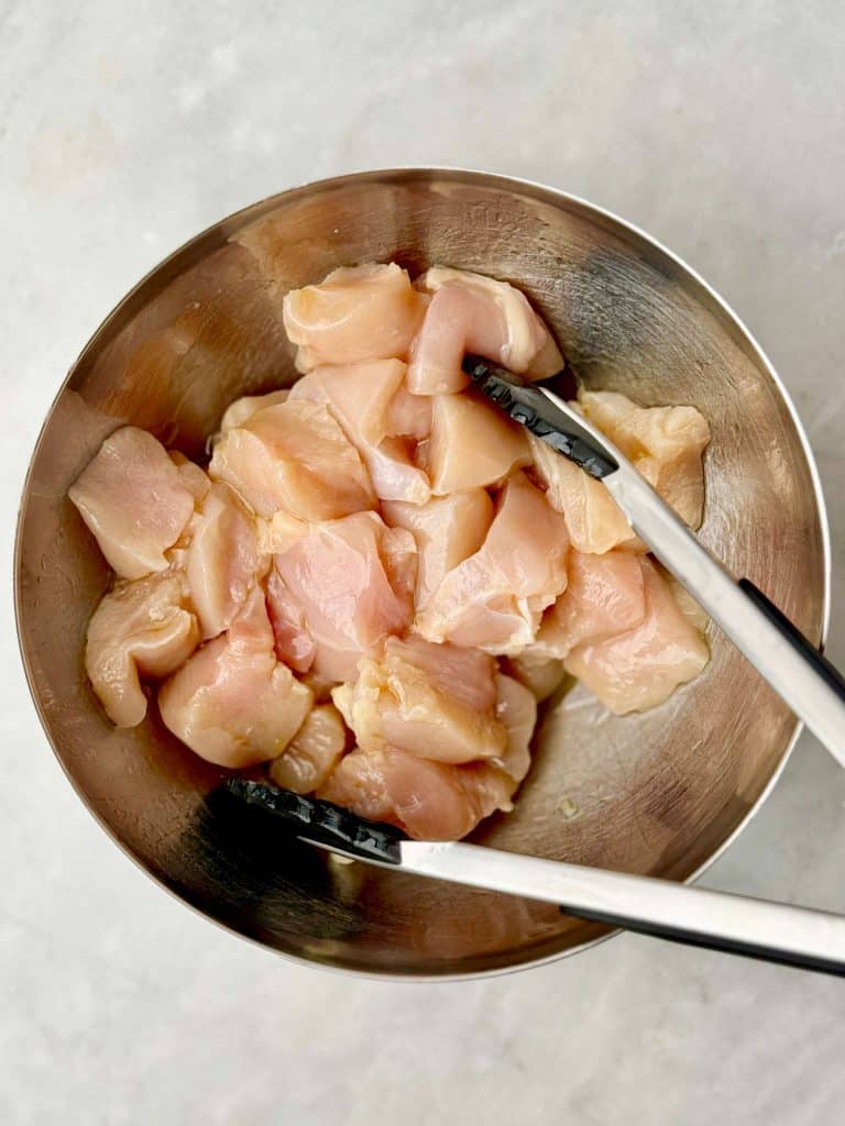 Cubed boneless skinless chicken breast ready to be seasoned for air fryer buffalo chicken.