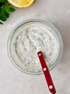 Creamy Greek yogurt ranch with fresh herbs in a glass jar.