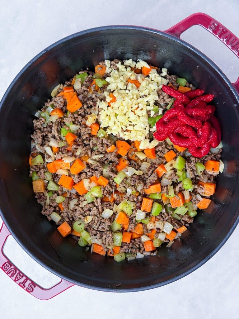 Garlic and tomato paste added to ground beef and vegetables for rich cabbage soup flavor
