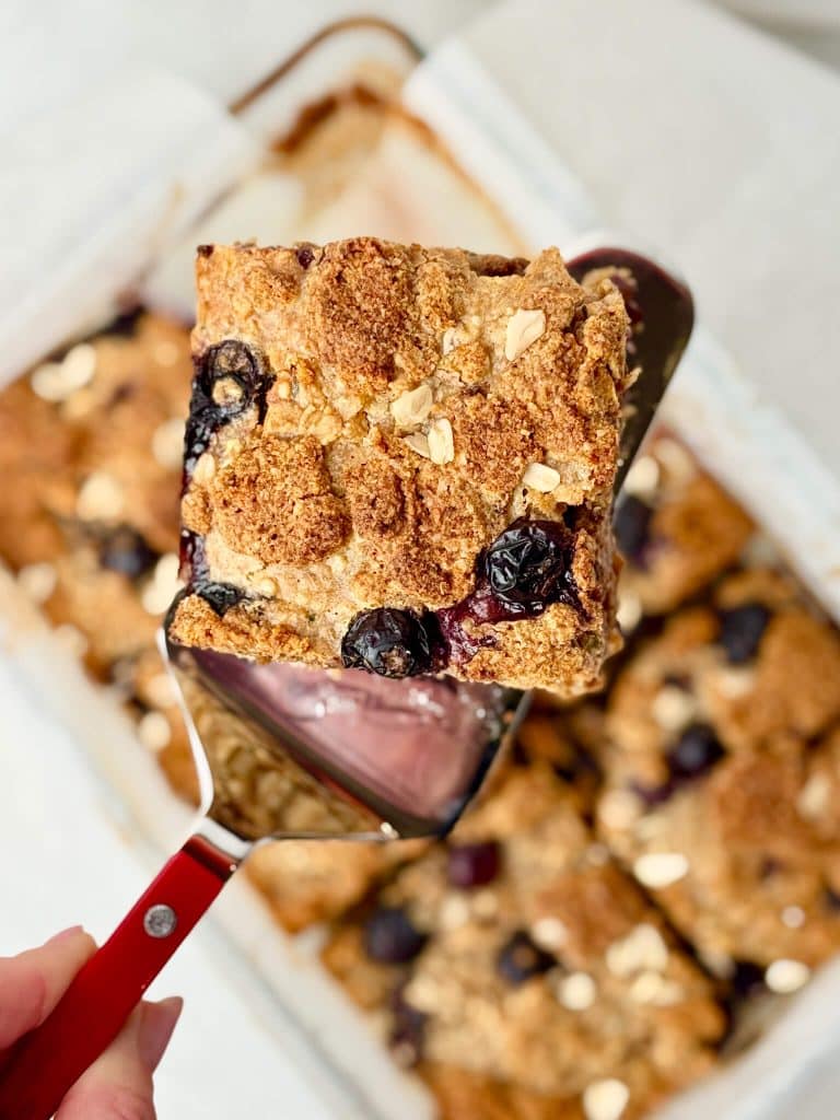Close-up of a slice of high-protein blueberry baked oatmeal with crumbly streusel and juicy blueberries.