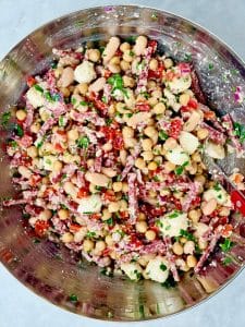 La Scala dense bean salad tossed together with chickpeas, cannellini beans, salami strips, mozzarella pearls, roasted red peppers, and fresh parsley.